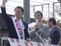 会場入り口で演説する尾立源幸参議院予定候補者（左）と山本